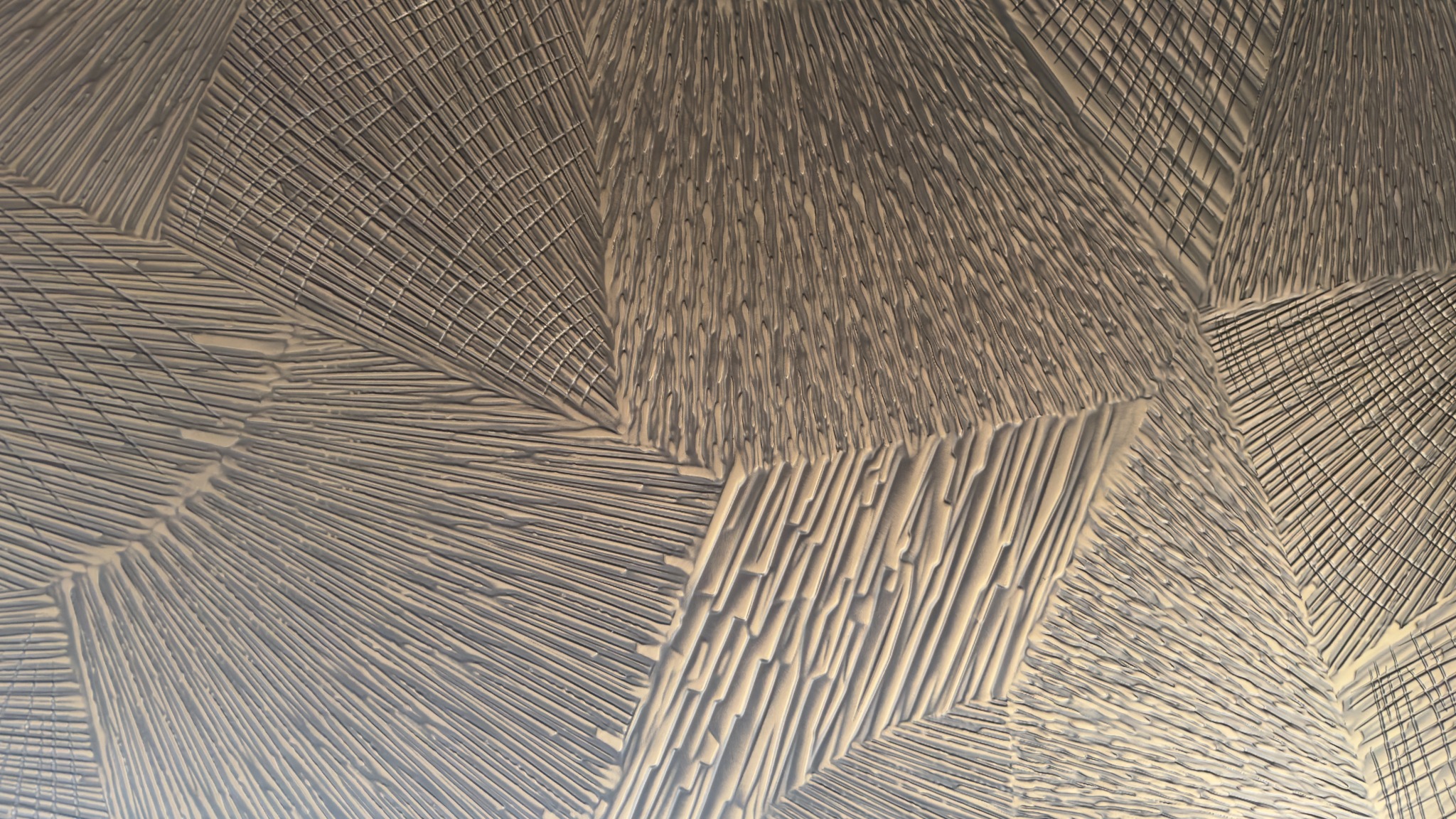 Intersecting linear relief patterns on a bronze-tone surface