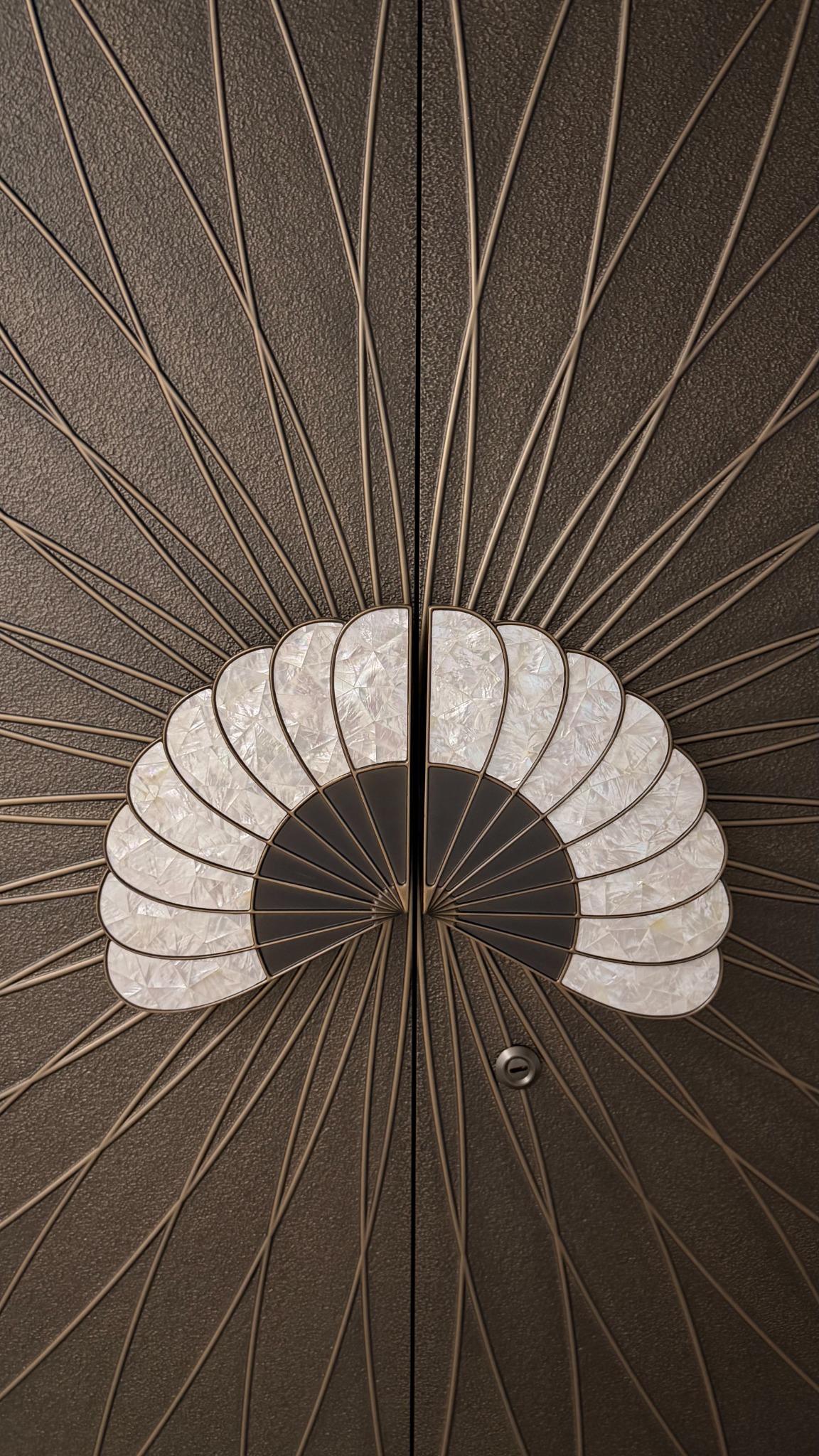 Full-height entrance with radial sculpted lines and a fan-shaped metal motif