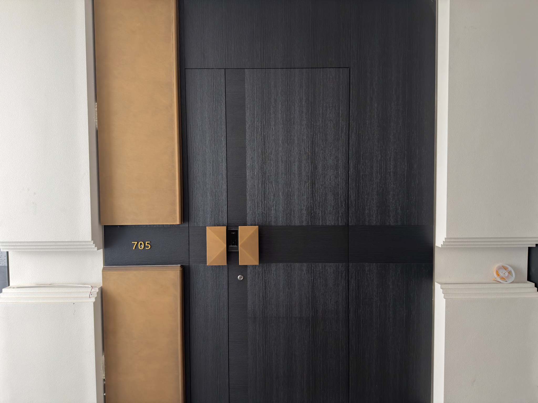 Dark door, bronze handle and surrounding panels composed together in the EPIN TOMCIM showroom
